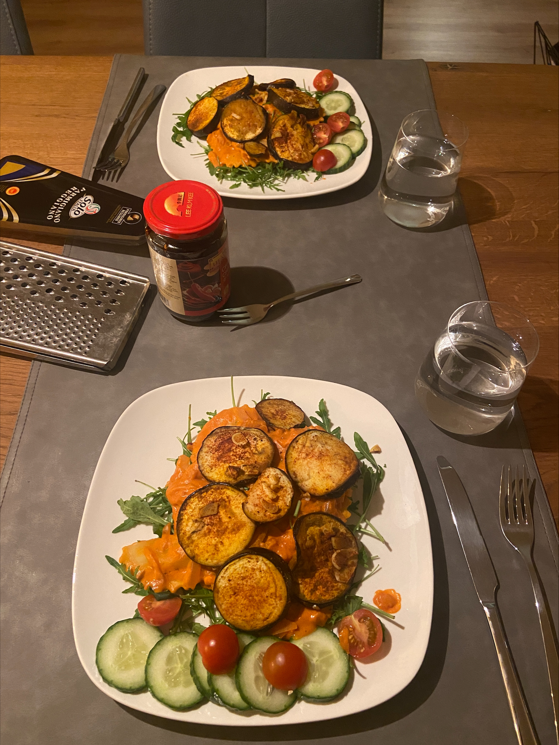 Two dinner plates on a table with ravioli and various vegetables on them